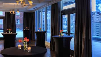 A modern hotel lobby with large windows, round tables with candles, and a city view.