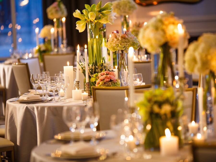 Une table à manger décorée avec des bougies, de la verrerie et des arrangements floraux.
