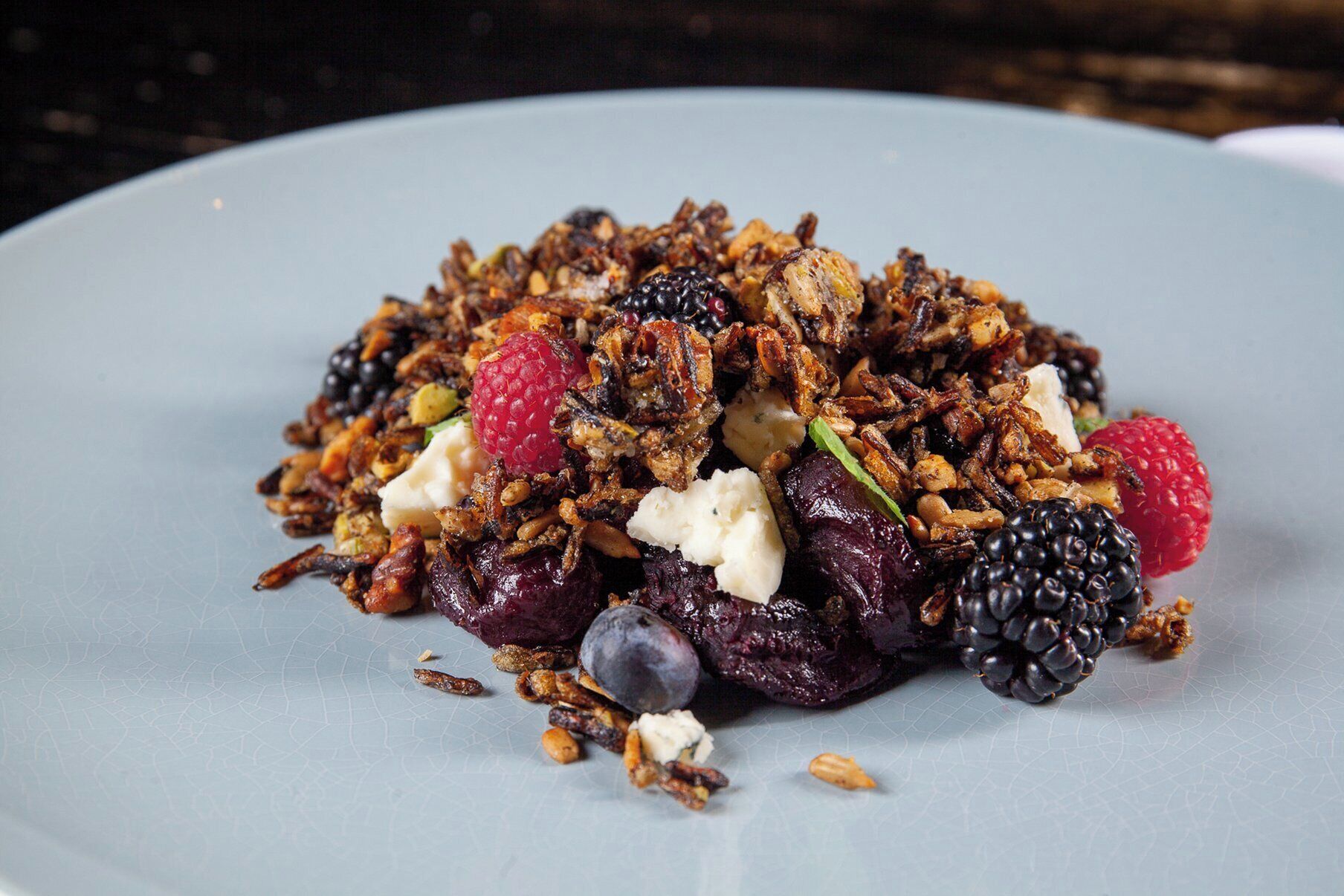 Um prato de granola com frutas vermelhas e nozes.
