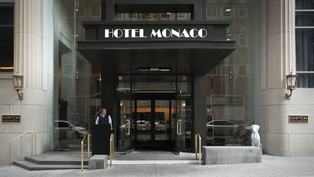 The entrance of the Hotel Monaco with a grand facade, a receptionist at the entrance, and a statue of a dog on the right. - Kimpton Hotel Monaco Pittsburgh by IHG (Pittsburgh)