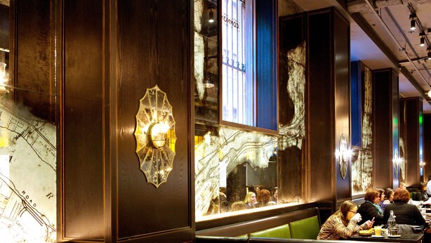 A restaurant interior with wooden paneling, a map on the wall, and diners seated at tables. - Kimpton Hotel Monaco Pittsburgh by IHG (Pittsburgh)