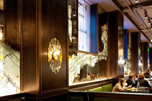 A restaurant interior with wooden paneling, a map on the wall, and diners seated at tables. - Kimpton Hotel Monaco Pittsburgh by IHG (Pittsburgh)