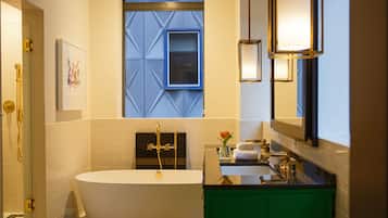 A modern bathroom with a freestanding bathtub, a vanity with a green cabinet, and a window with a geometric blue pattern.