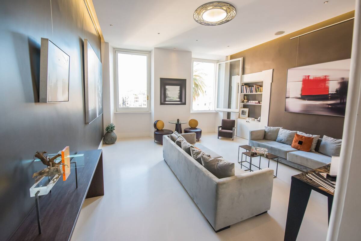 A modern living room with a grey sofa, a coffee table, and a bookshelf.