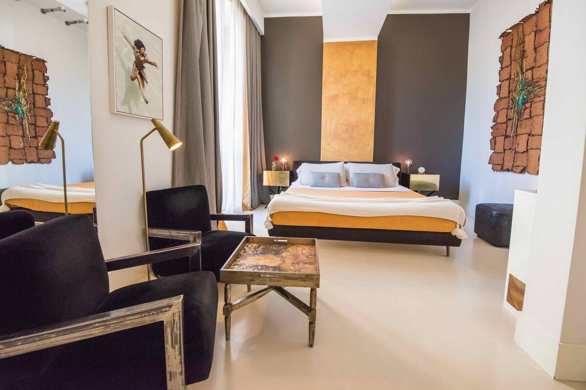 A modern hotel room with a large bed, a desk, and a chair. There are two bedside tables with lamps.