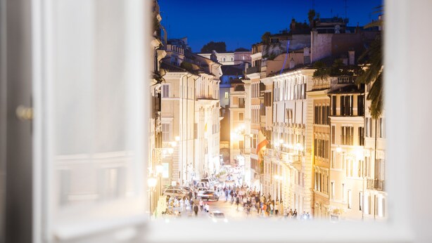 Une rue animée, illuminée de mille feux, bordée de bâtiments historiques, où l’on peut voir une foule de personnes et des voitures.