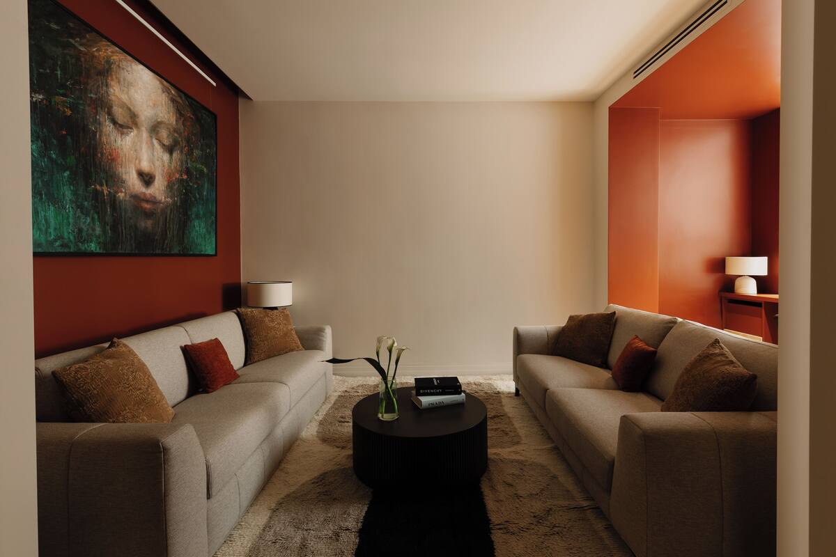 A modern living room with two sofas, a coffee table, and a large painting on the wall.