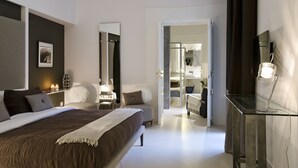 Une chambre moderne avec un grand lit, des tables de chevet, un miroir et un bureau en verre avec une lampe.