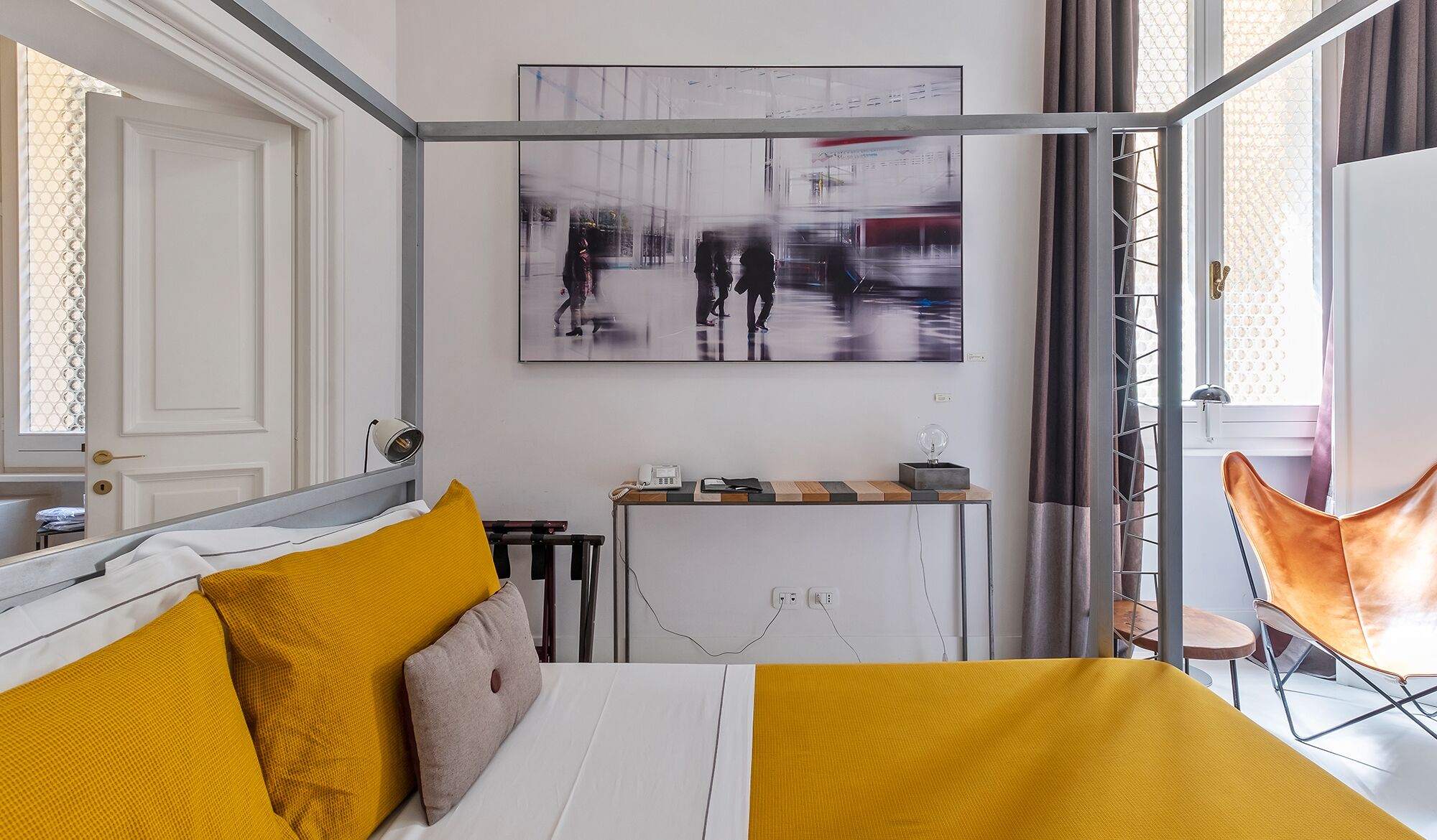 Une chambre d’hôtel moderne, équipée d’un lit, d’un bureau et d’une grande fenêtre.