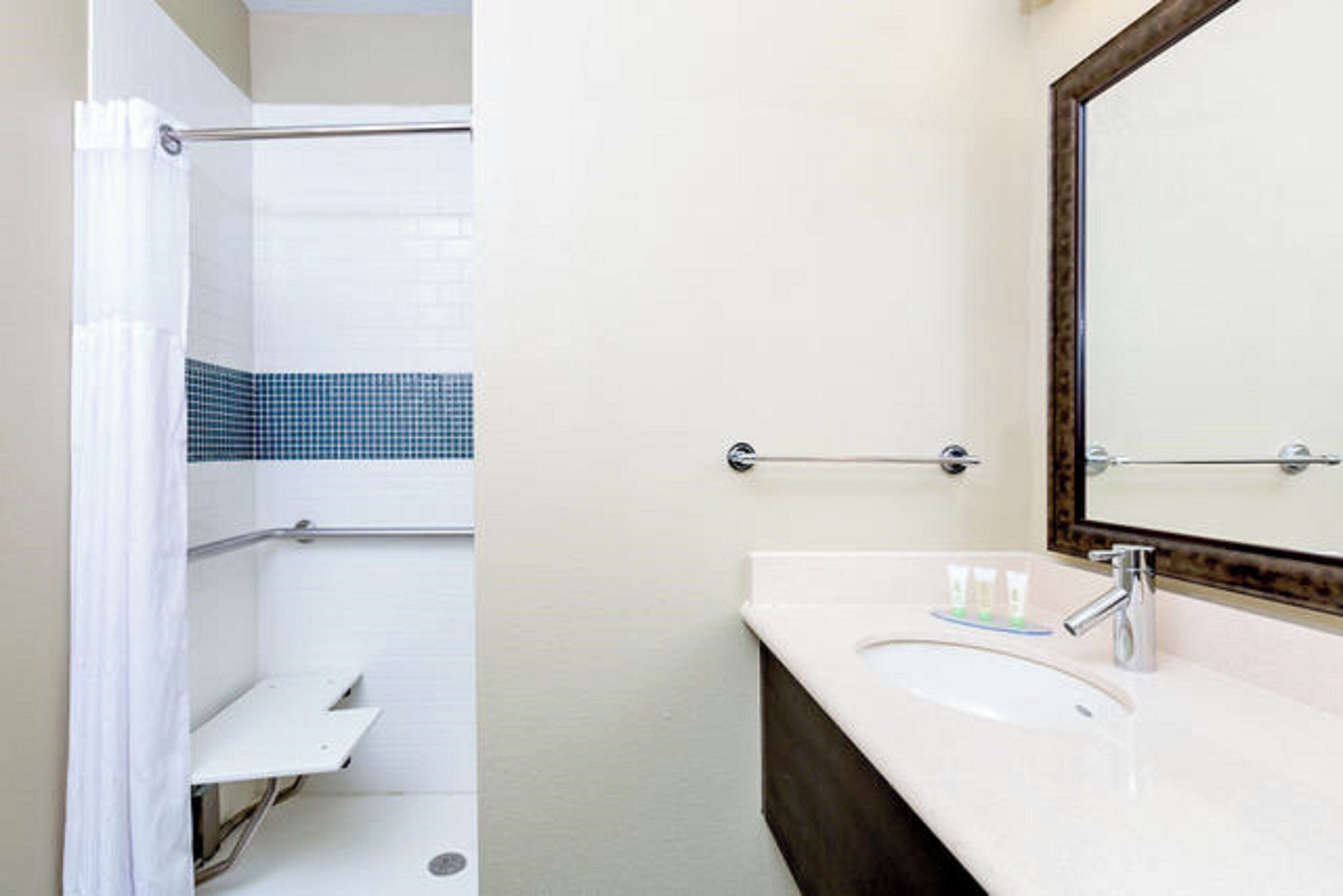 A bathroom with a shower, a sink, and a mirror.