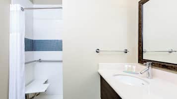 A bathroom with a shower, a sink, and a mirror.