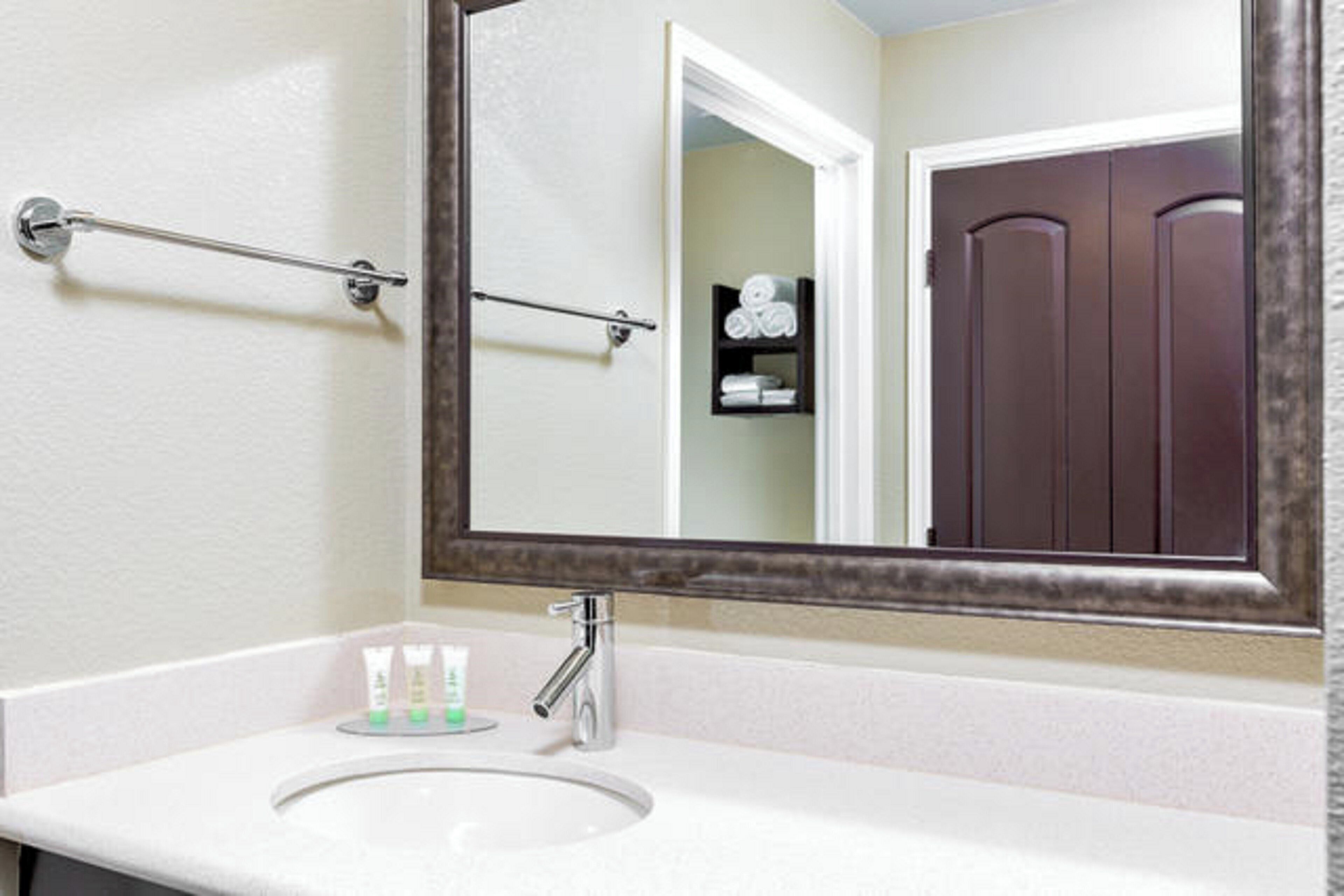 A bathroom with a white sink, a large mirror, and a towel rack.