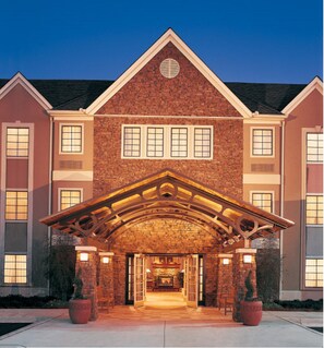 A large brick building with a prominent entrance featuring a wooden archway and a fireplace.