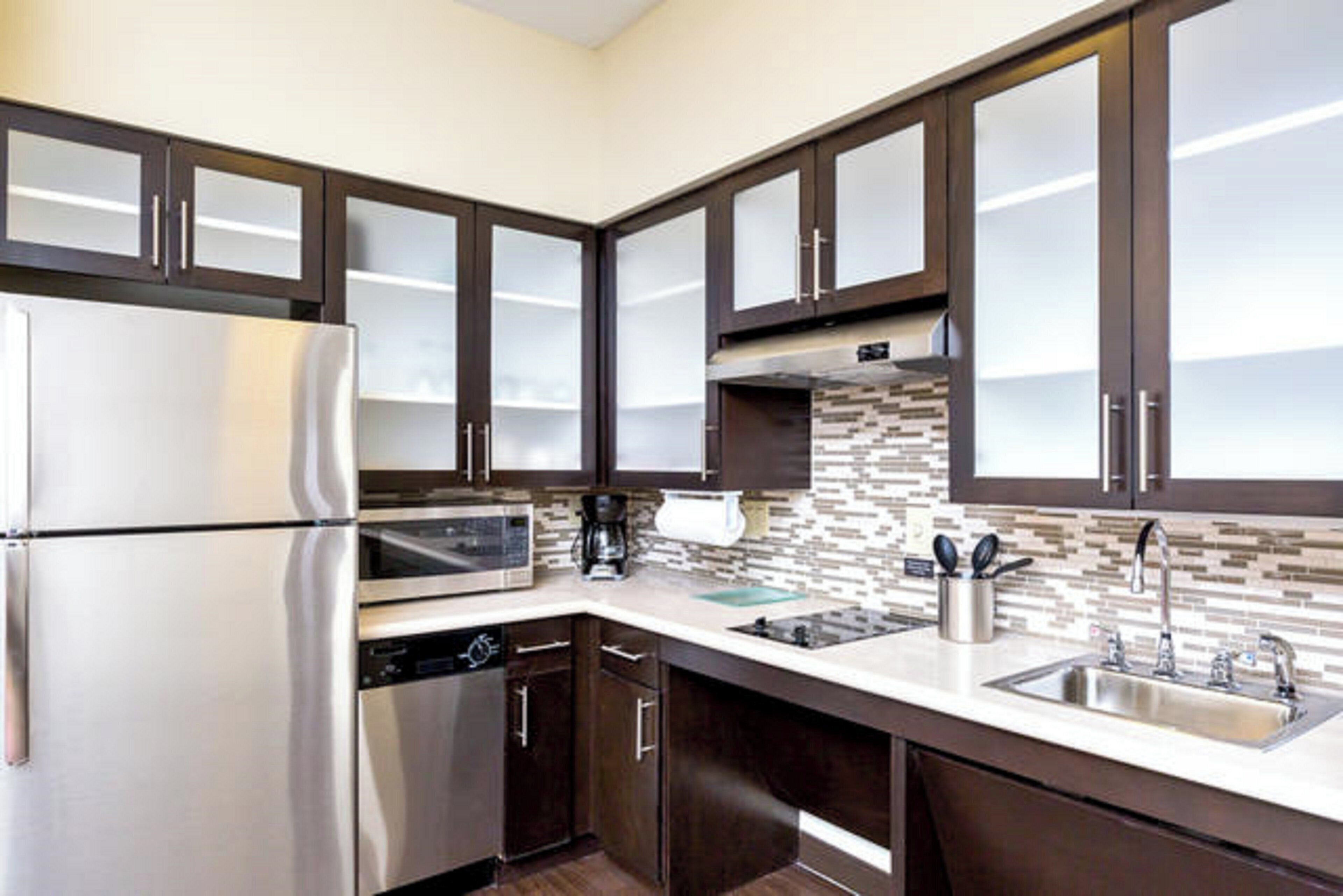 A modern kitchen with stainless steel appliances, dark wooden cabinets, and a tiled backsplash.