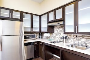 Una cocina moderna con electrodomésticos de acero inoxidable, gabinetes de madera oscura y un salpicadero de azulejos.