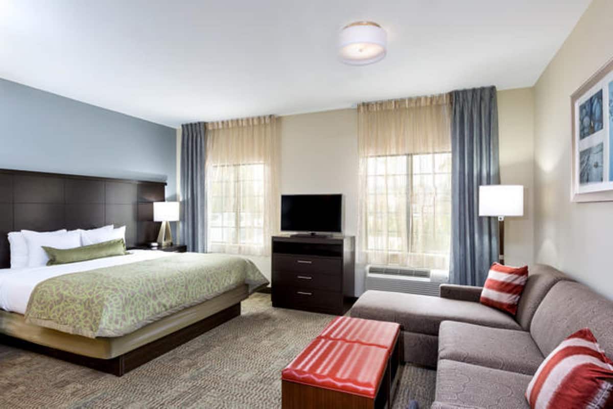 A hotel room with a bed, a TV, a sofa, and a desk.