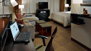 A hotel room with a bed, a desk with a laptop, a TV, a dresser, and a chair. - Staybridge Suites College Station by IHG (College Station)