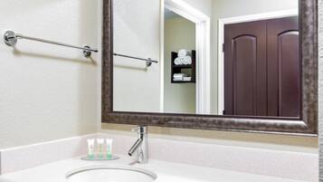 A bathroom with a white sink, a large mirror, and a towel rack.