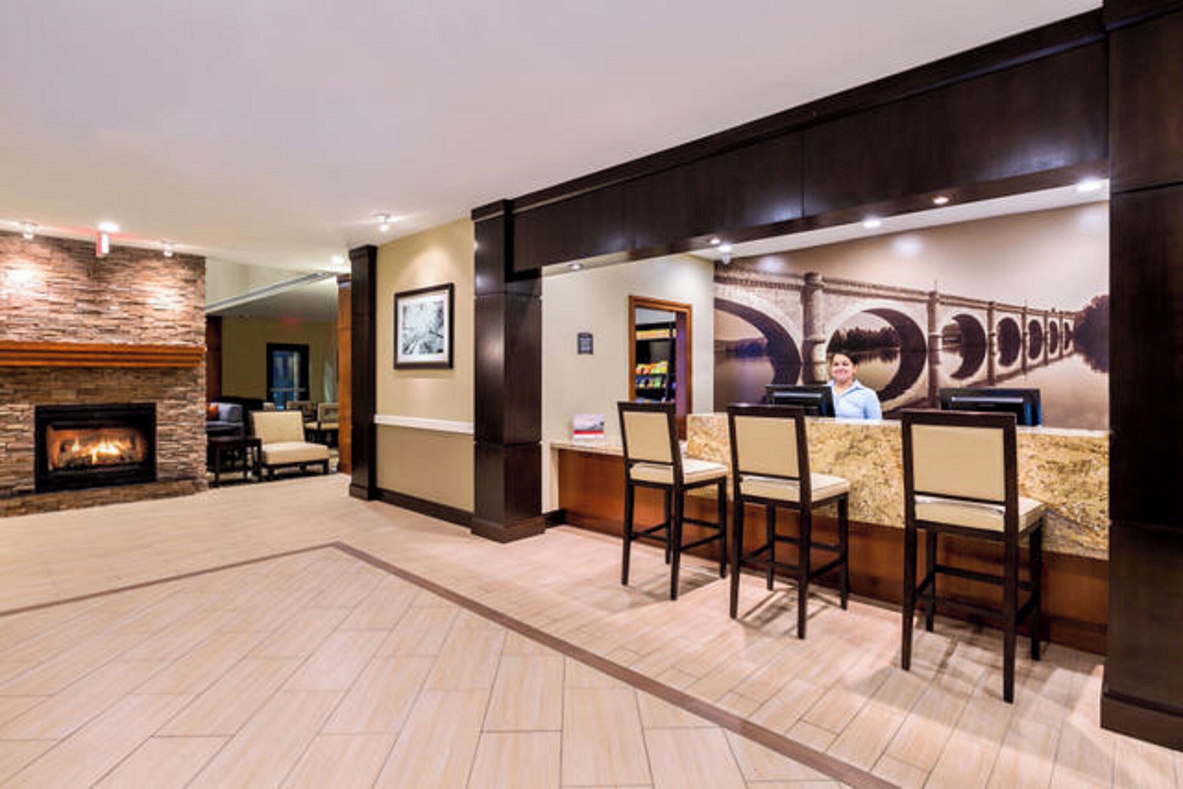 Una hall d'albergo con reception, sedie, camino e un grande murale.
