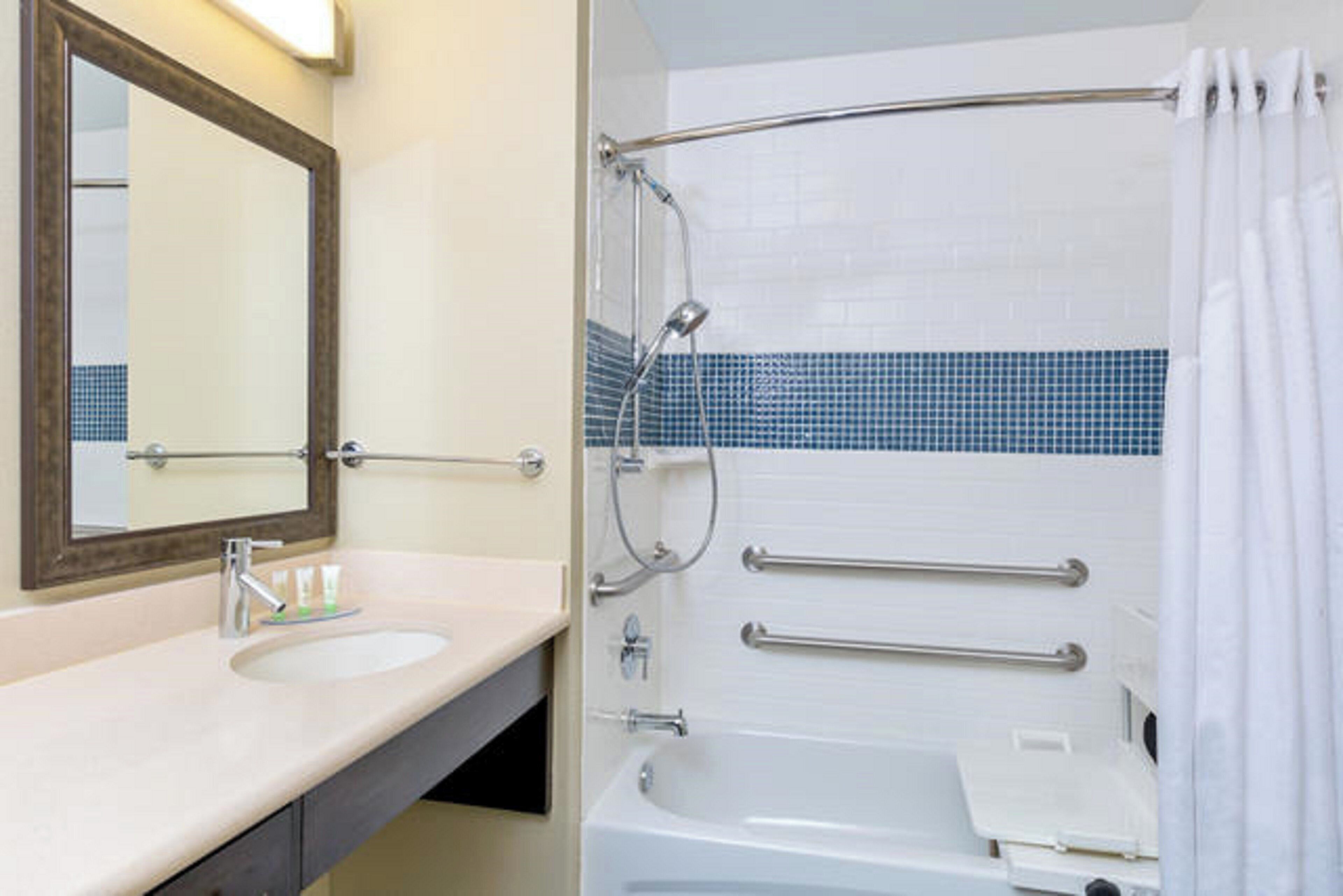Un bagno con lavandino, specchio e vasca da bagno con tenda doccia.