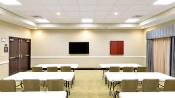 Une salle de conférence équipée de tables et de chaises, d’un téléviseur à écran plat et d’une porte.