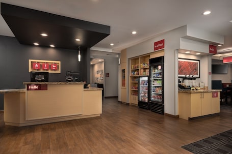 A hotel reception area with a reception desk, a refrigerator stocked with beverages, and a coffee machine.