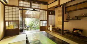 A traditional Japanese room with tatami flooring, sliding doors, and a view of a garden. - naokonoza Bettei Umekoji (Kyoto)