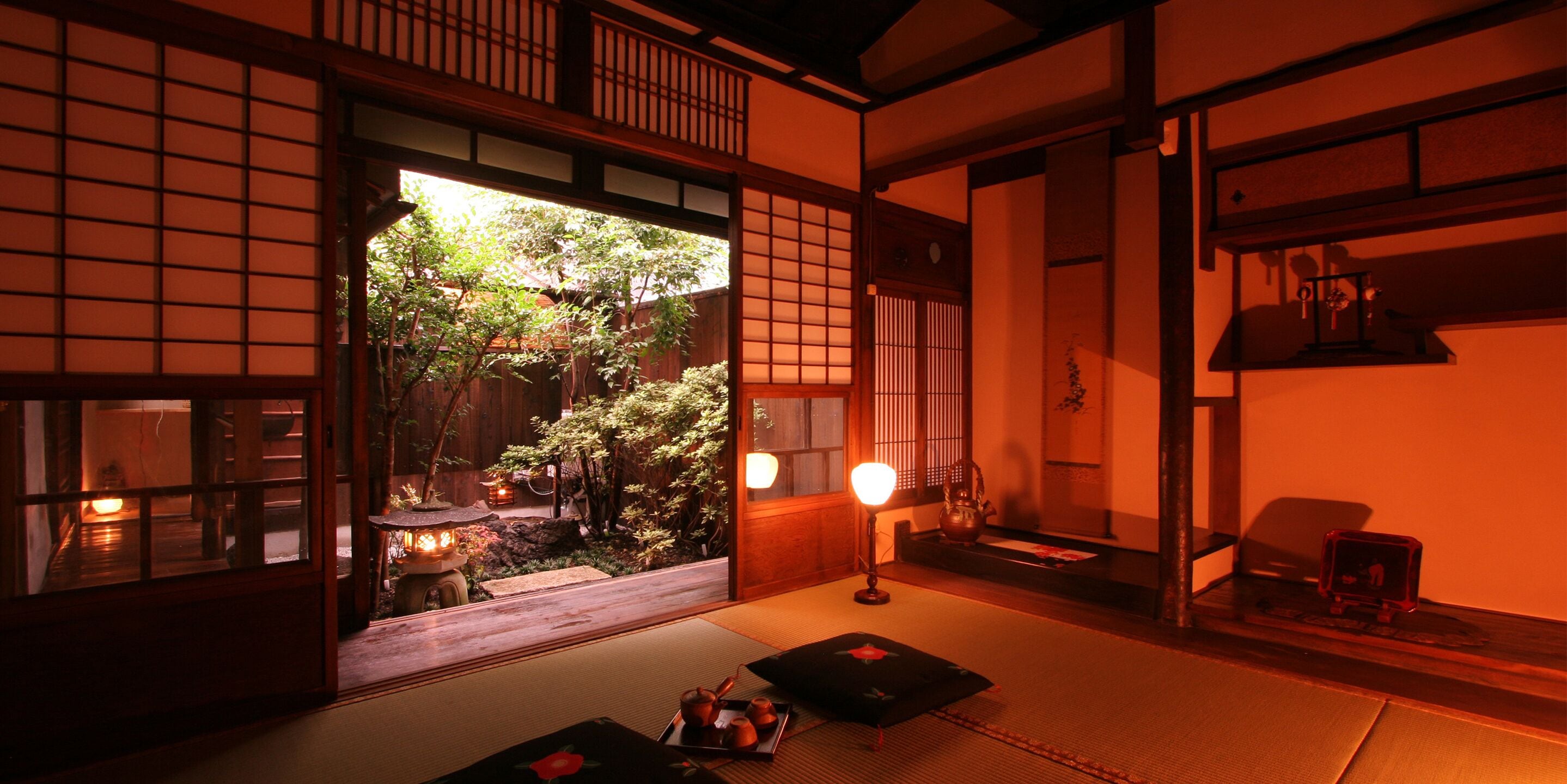 A traditional Japanese room with tatami flooring, a shoji screen door, and a view of a garden.