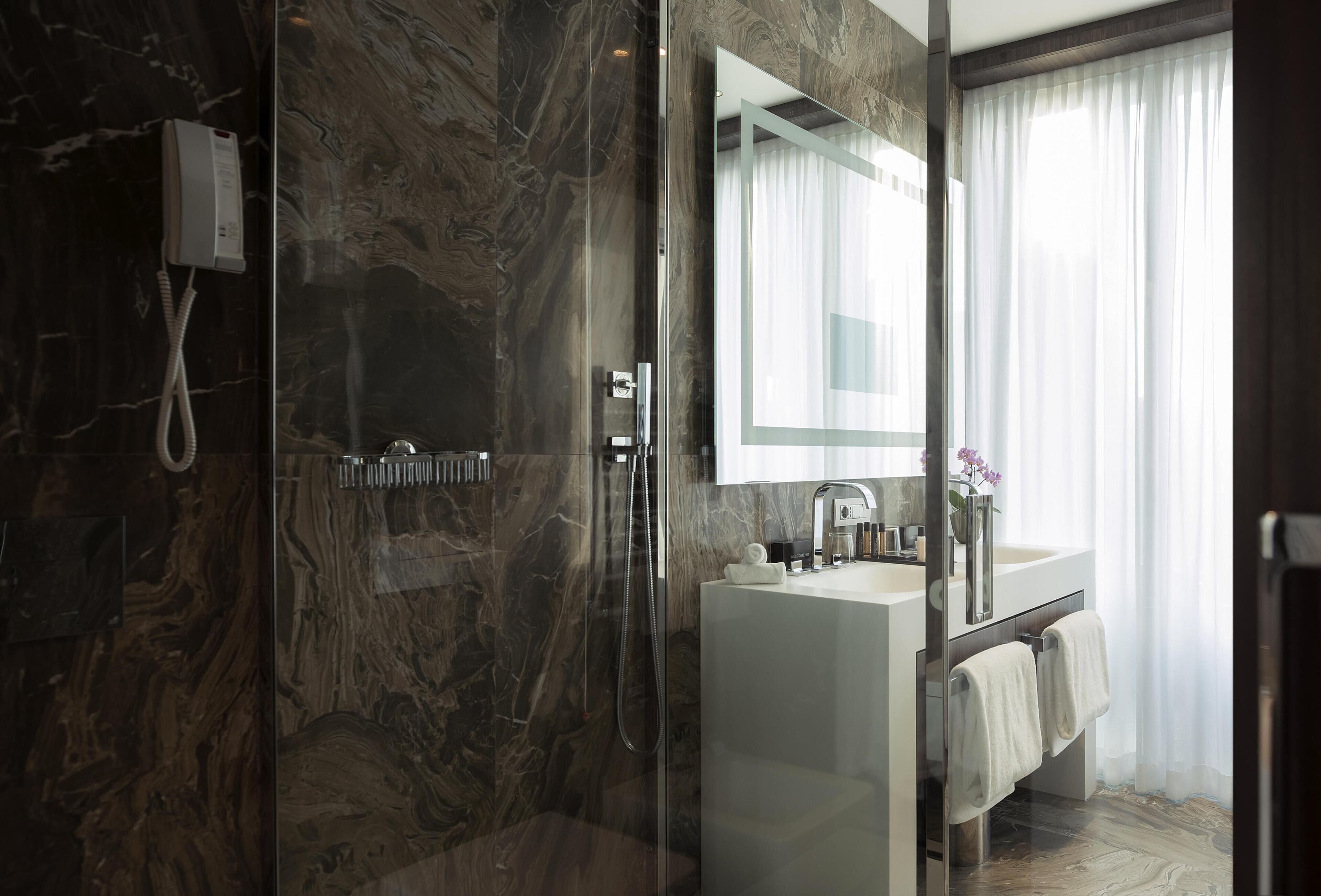 A modern bathroom with a glass-enclosed shower, a white sink, and a large mirror.
