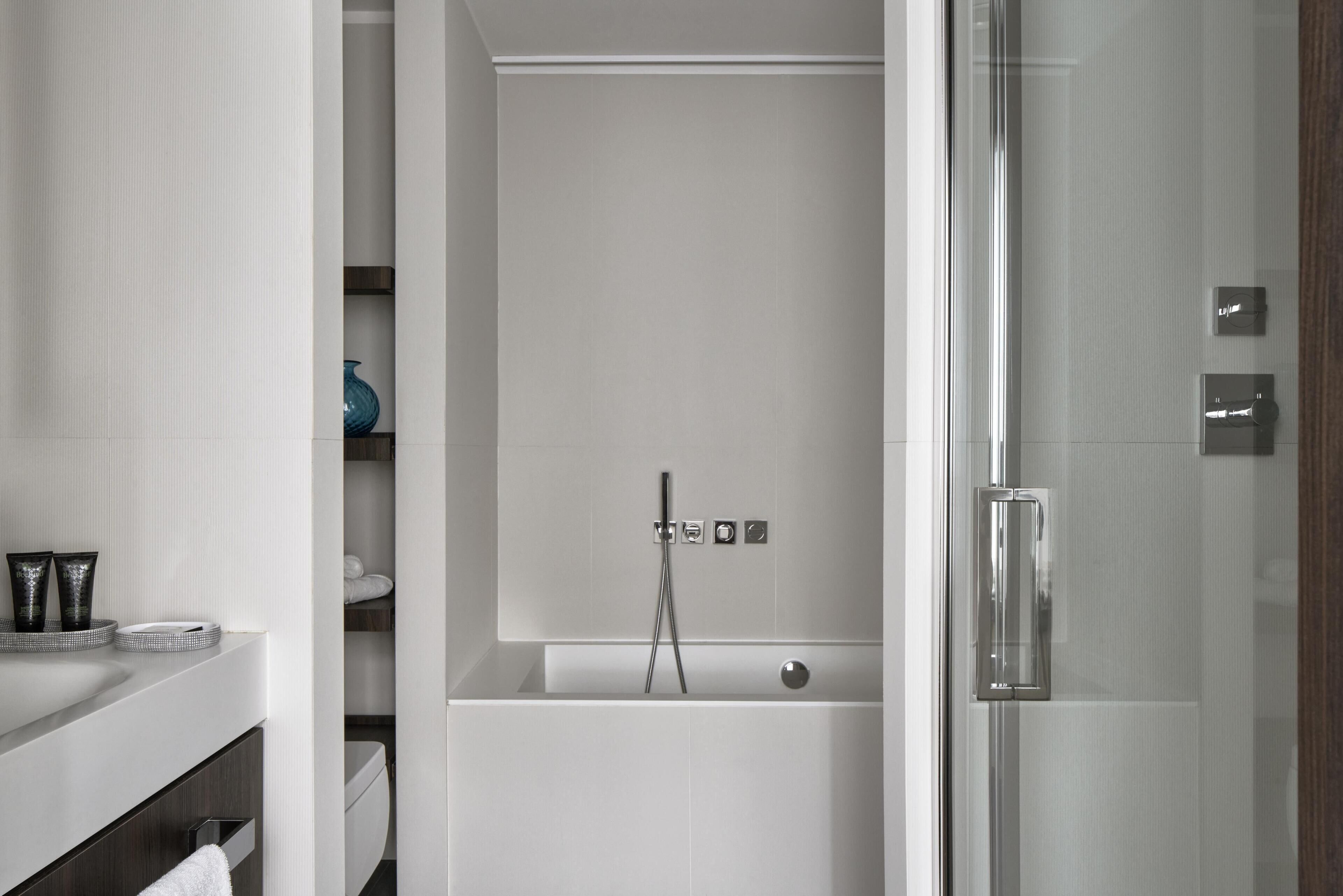 Un baño moderno con cabina de ducha de vidrio, una bañera blanca y un tocador con toallero.