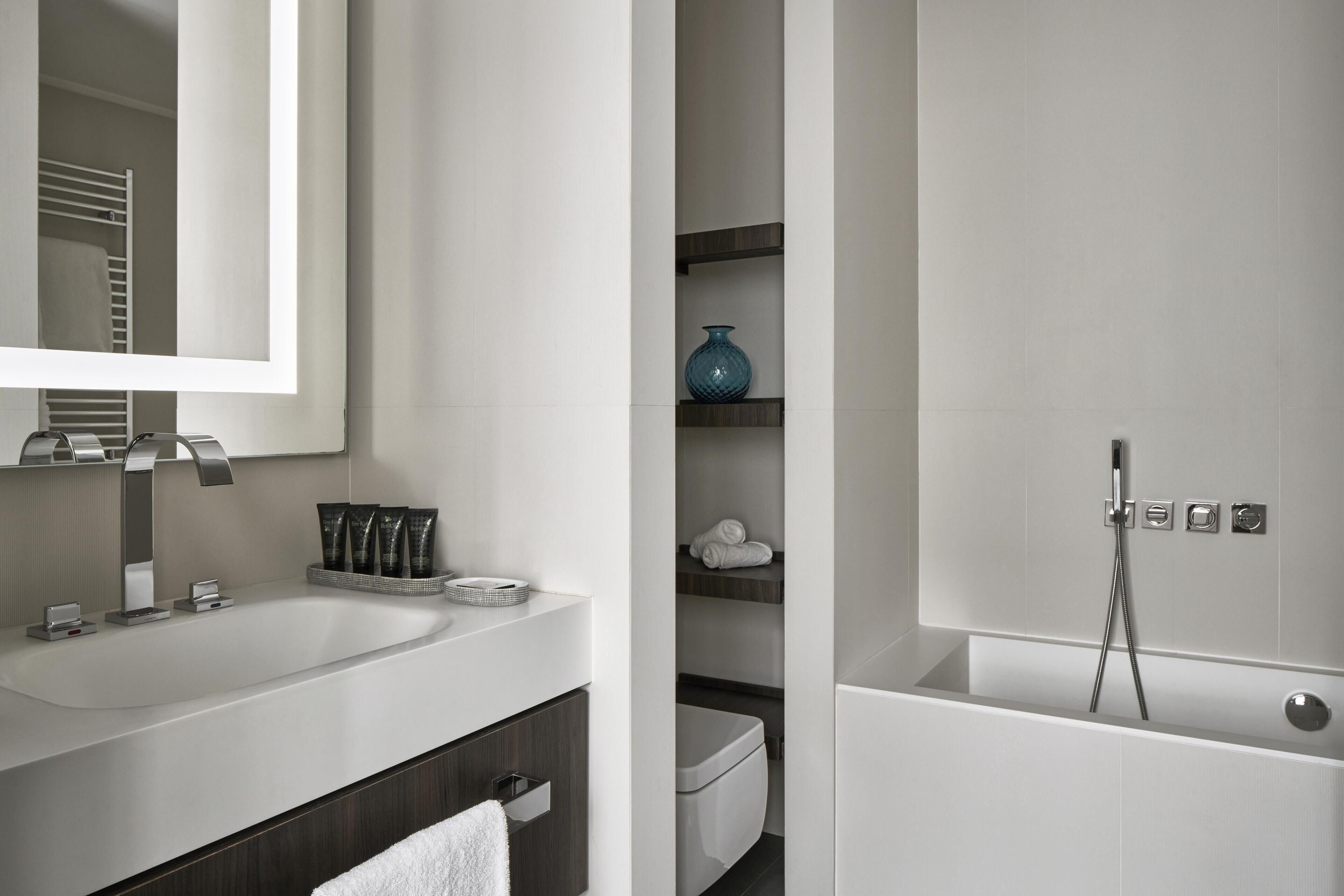 A modern bathroom with a large sink, mirror, and bathtub.