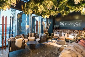 A cozy lounge area with seating, skis, and a sign for 'The Organics by Red Bull.' - Hyatt Centric Milan Centrale (Milan)