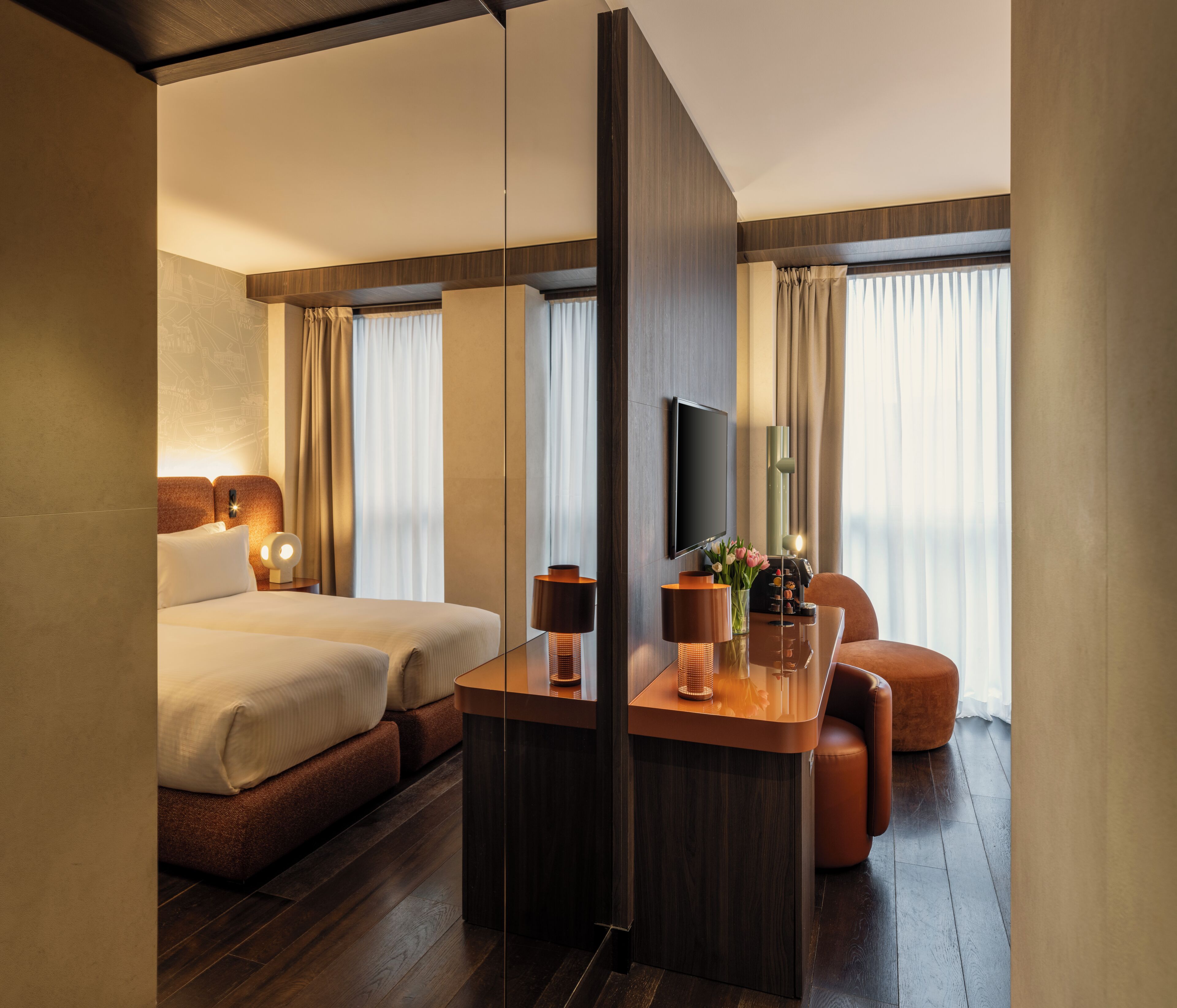 Une chambre d’hôtel équipée d’un lit, d’un bureau, d’une chaise, d’une télévision et d’une grande fenêtre avec des rideaux.