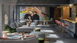 A modern lounge area with sofas, chairs, a bar, and a colorful mural. - Hyatt Centric Milan Centrale (Milan)