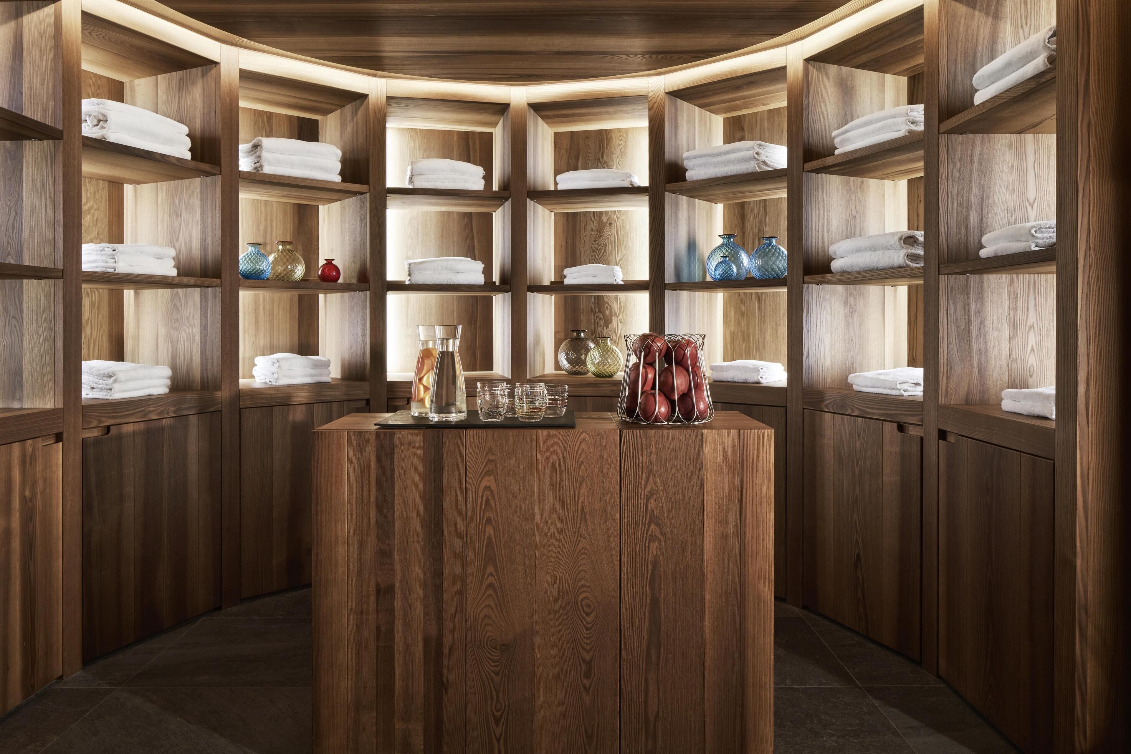 A wooden interior with shelves holding towels and decorative items.
