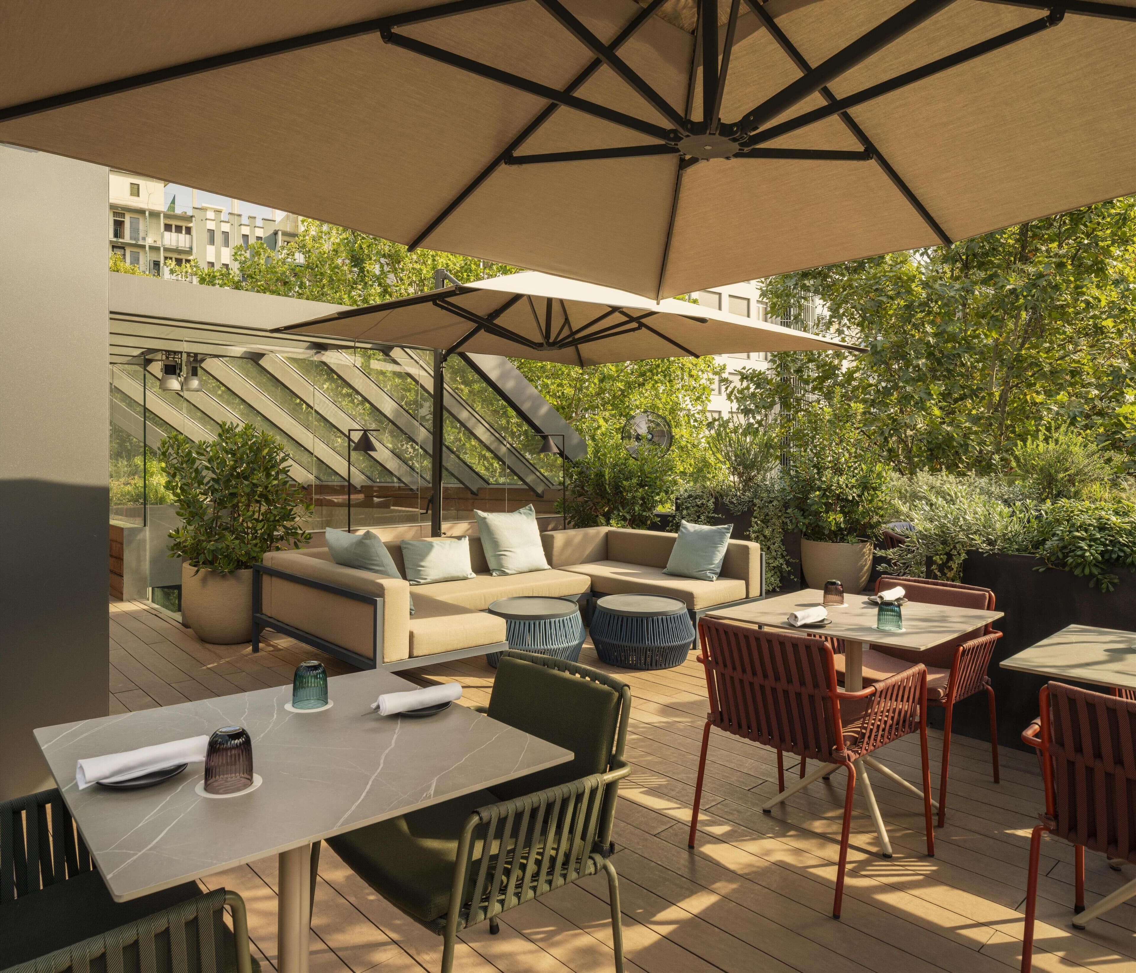 An outdoor patio with a sofa, chairs, a table, and a large umbrella.