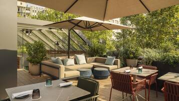 An outdoor patio with a sofa, chairs, a table, and a large umbrella.
