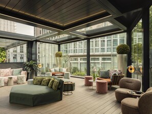 En moderne tagterrasse med glasloft, behagelige siddepladser og udsigt over bybilledet.