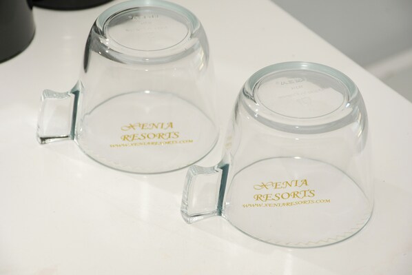 Two clear glass mugs with handles, each labeled 'XENIA RESORTS' and a website address. - Porto Evia Boutique Hotel by Xenia Resorts (Eretria)