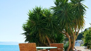 A poolside area with a tiled edge, two wicker chairs, and a table. - Porto Evia Boutique Hotel by Xenia Resorts (Eretria)