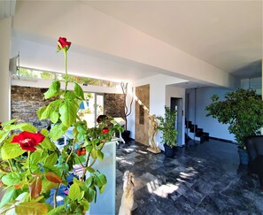 A spacious interior with a stone wall, a staircase, and potted plants. - Porto Evia Boutique Hotel by Xenia Resorts (Eretria)