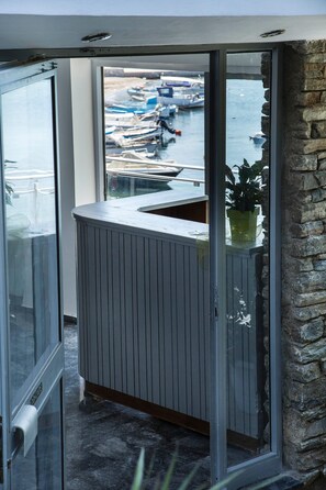 A balcony with a view of boats, a potted plant, and a stone wall. - Porto Evia Boutique Hotel by Xenia Resorts (Eretria)