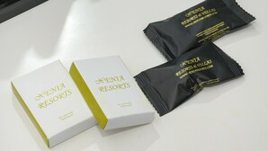 Two white boxes and two black packets with 'Xenia Resorts' branding, placed on a white surface. - Porto Evia Boutique Hotel by Xenia Resorts (Eretria)