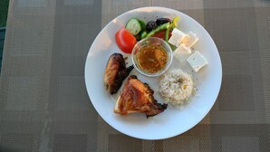 A plate with grilled chicken, rice, vegetables, and feta cheese. - Porto Evia Boutique Hotel by Xenia Resorts (Eretria)