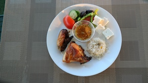 A plate with grilled chicken, rice, vegetables, and feta cheese.