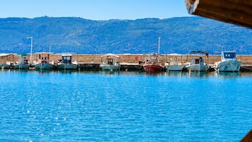 Un puerto con barcos amarrados, un cielo azul despejado y un paisaje montañoso al fondo.