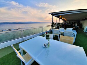 A terrace with a table set for two, overlooking a body of water and a distant shoreline. - Porto Evia Boutique Hotel by Xenia Resorts (Eretria)