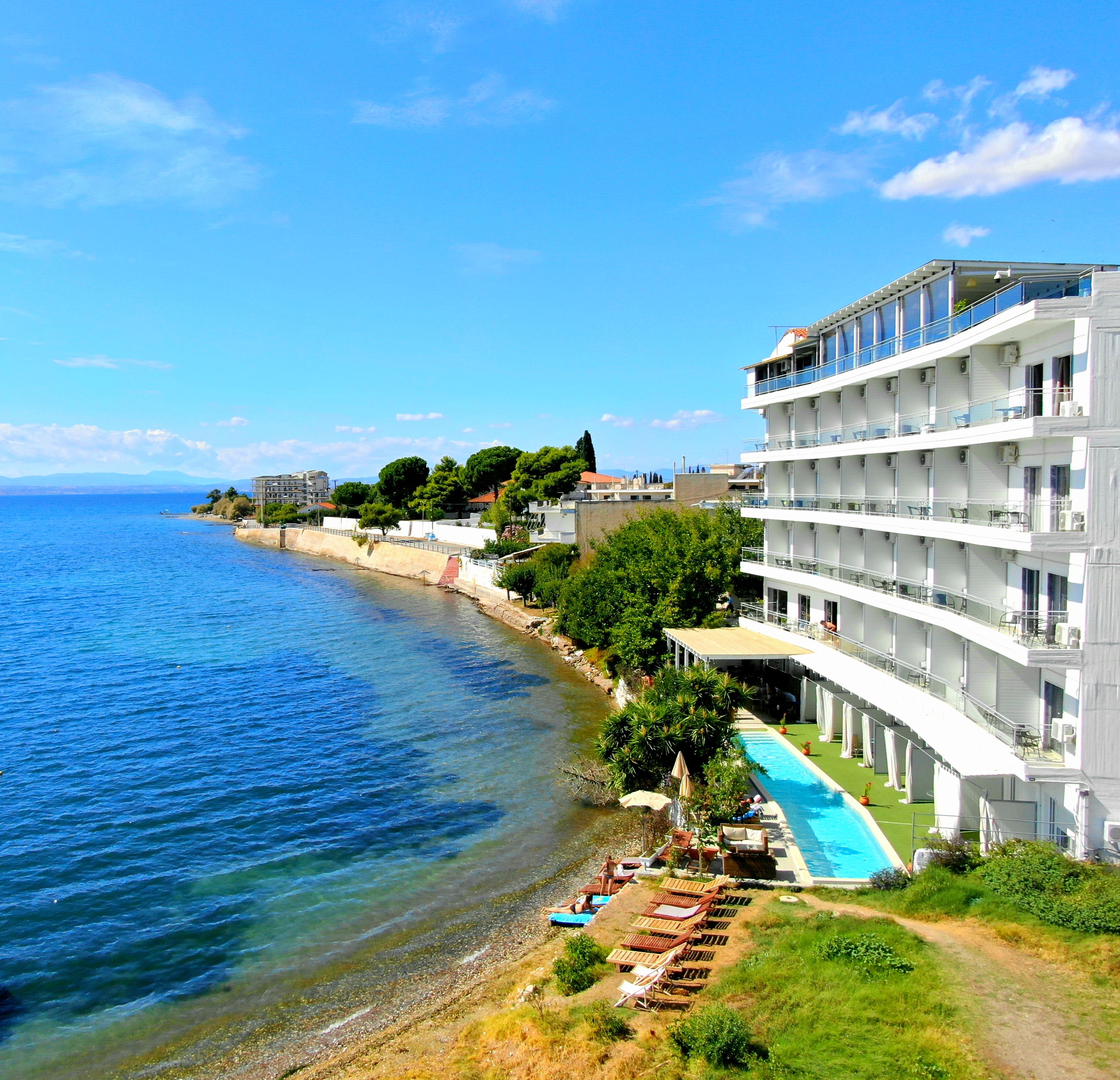 Un hotel a la costa amb piscina, diversos balcons i vista al mar.