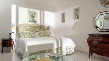A bedroom with a bed, a dresser, a nightstand, and a glass table with books.