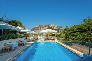 Una piscina al aire libre, sombrillas, sillones reclinables de piscina